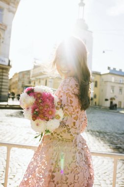 Buket çiçek tutan pembe dantel elbise gülümseyen genç modeli