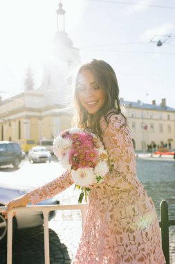 Gülümseyen genç buket çiçek tutan dantel elbise modeli