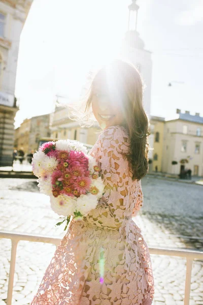 Buket çiçek tutan pembe dantel elbise gülümseyen genç modeli