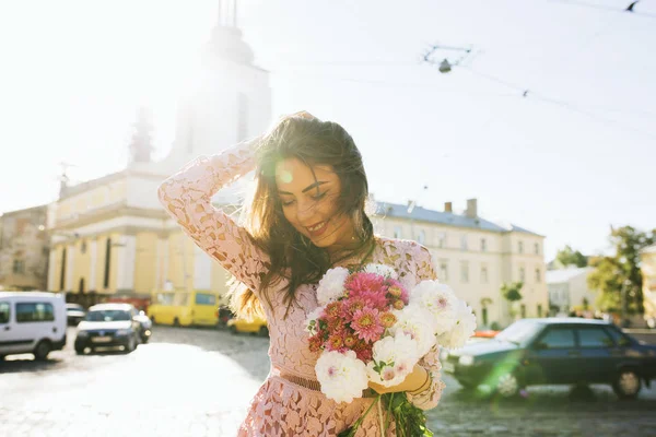 Modelo sorridente elegante em vestido de renda segurando buquê de flores — Fotografia de Stock