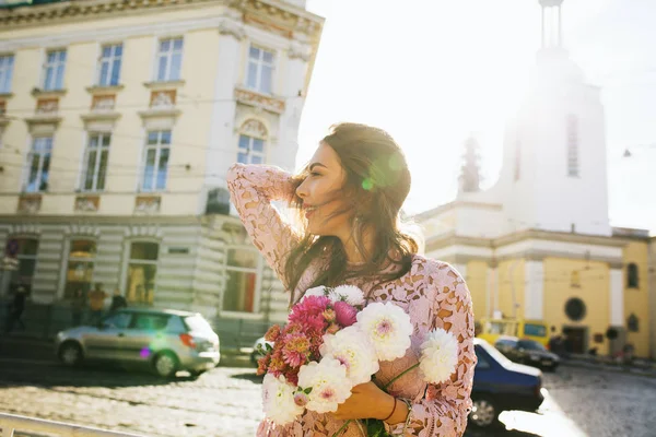 Dantel elbiseli çekici esmer manken elinde flowe buketi tutuyor.