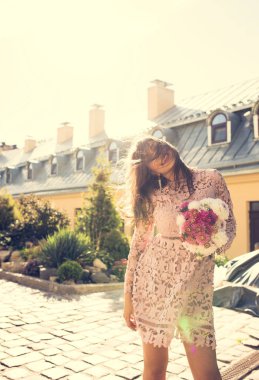 Güzel, mutlu bir manken, dalgalı saçları ve elinde bir buket çiçekle.