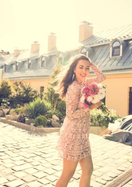 Elegant modeli ışık ışınları çiçeklerle poz gülümseyerek. Vint