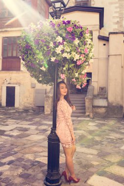 Güzel esmer model Güneş ışınlarının yatakta çiçek yakınındaki poz