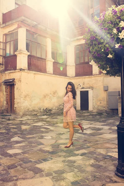 Linda senhora morena com posando perto de canteiro de flores em raios de sol . — Fotografia de Stock