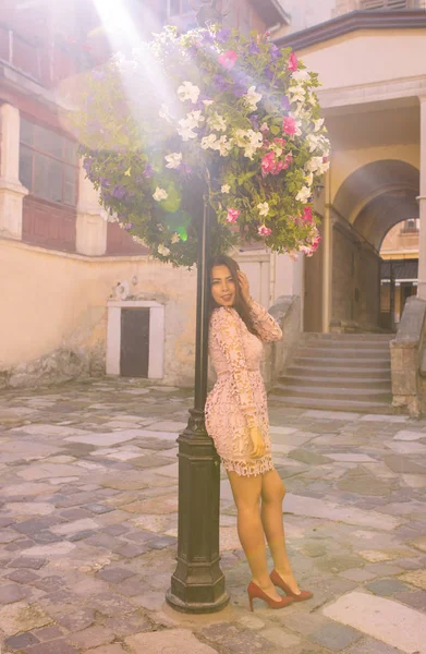 Schönes junges Model trägt modisches Kleid, posiert in der Nähe von Blumen — Stockfoto