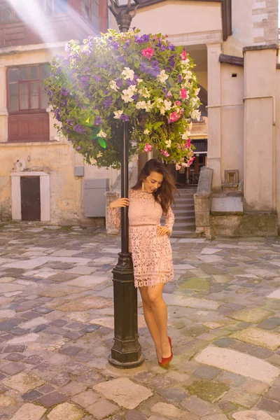 Modelo jovem bonita em vestido de renda posando perto de canteiro de flores em r — Fotografia de Stock