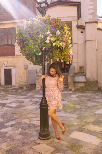 Atemberaubendes junges Model posiert in der Nähe von Blumenbeeten in Lichtstrahlen — Stockfoto