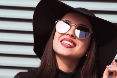 Güneş gözlüğü ve şapka sokağın poz genç model gülümseyen. 