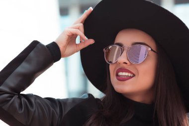 Mutlu esmer modeli Güneş gözlüğü ve şapka sokağın poz.