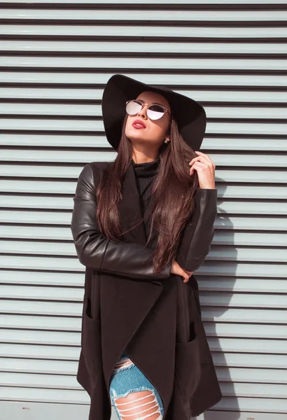 Kat, yırtık kot pantolon ve şapka ve poz çekici genç modeli giyer 