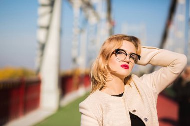 Bej bir palto ve gl genç kadınla göz alıcı parlak makyaj giyer