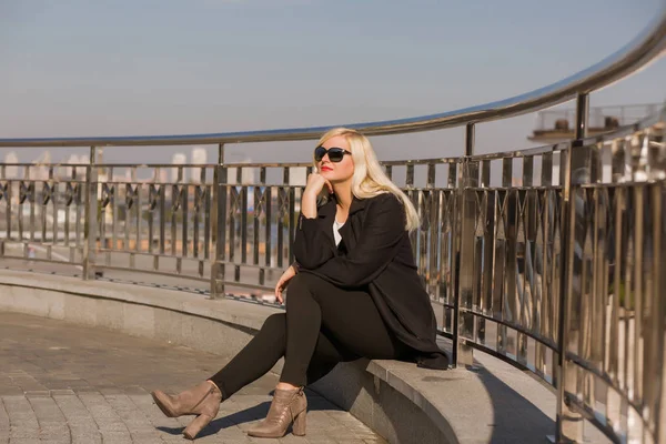 Elegant blond modell poserar i svart rock, bär solglasögon på ett — Stockfoto