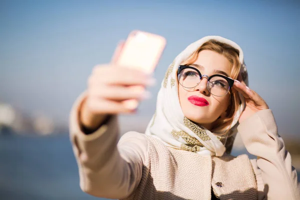 Pretty blonde woman taking selfie on mobile phone. Woman wears s — Stock Photo, Image