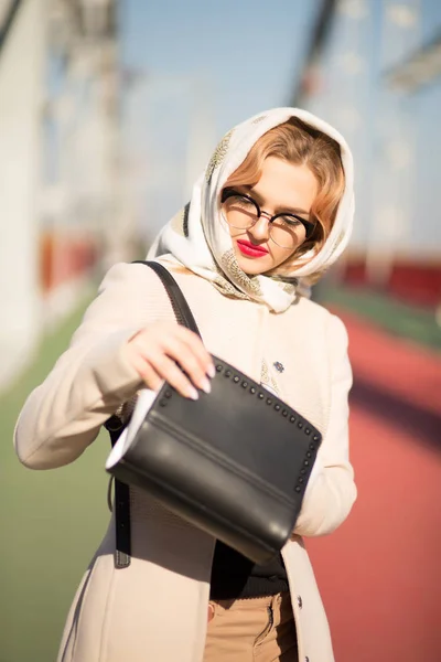 Fashionable dressed model looking into her handbag and wears bei — Stock Photo, Image