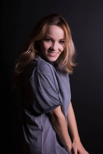 Lovely modelo jovem com cabelo loiro exuberante, usa camisa cinza, pos — Fotografia de Stock