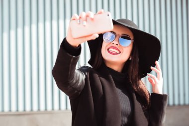 Mutlu esmer model alarak selfie üstünde hareket eden telefon. Kadın giyer 