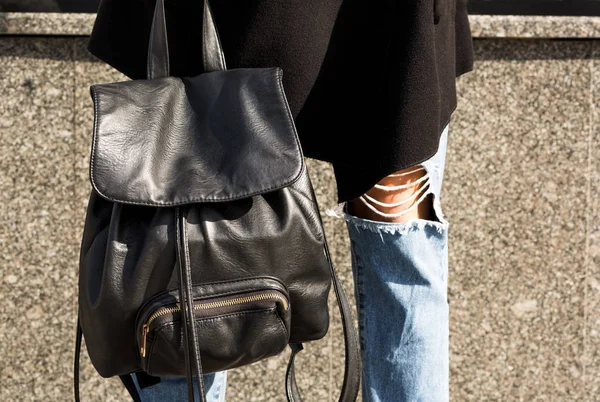 Närbild skott av svart läder ryggsäck på kvinnans ben — Stockfoto
