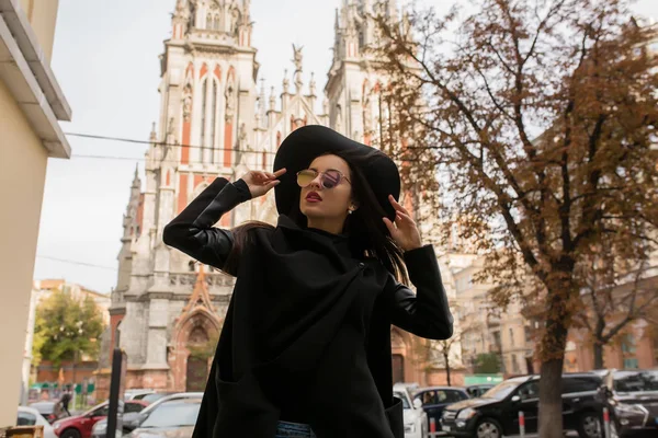 Уличный портрет привлекательной модели в модном черном пальто и хлеву — стоковое фото