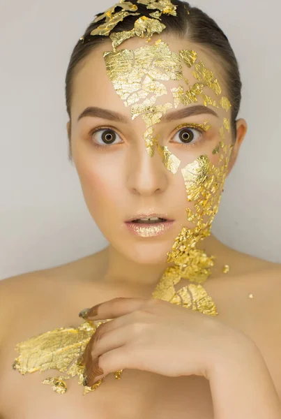 Emotional surprised woman with golden foil on her face — Stock Photo, Image