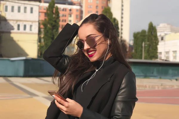 Lovely smiling model in glasses listen music on mobile telephone — Stock Photo, Image