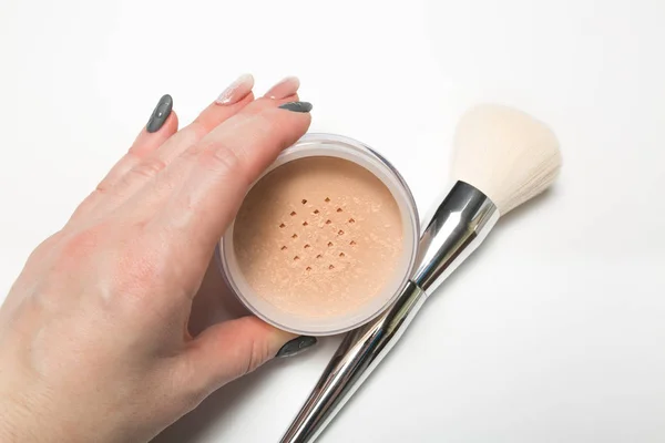 Mineral loose powder and cosmetic brush in woman's hand on a whi — Stock Photo, Image
