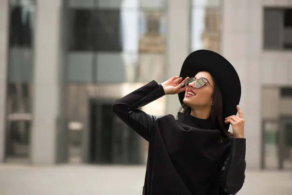 Mulher sorridente bonita em chapéu preto de abas largas e sol espelho — Fotografia de Stock