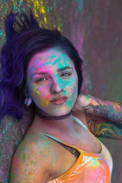 Wonderful woman covered with colorful Holi powder, lying on the