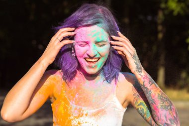 Neşeli kadın onun etrafında pembe ve yeşil Holi toz kaplı.