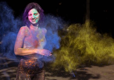 Mavi ve sarı Holi toz patla ile oynarken mutlu genç kadın