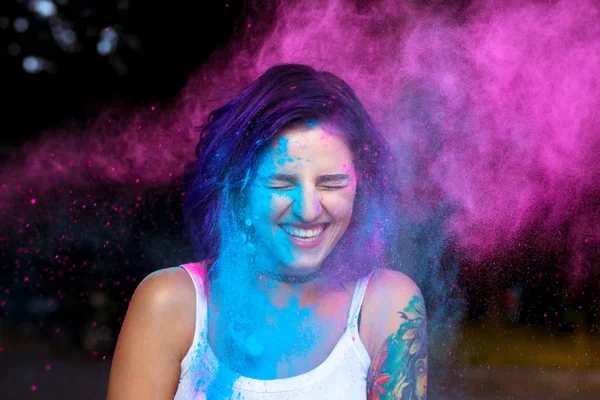 Riendo joven mujer con polvo seco Holi explotando a su alrededor — Foto de Stock