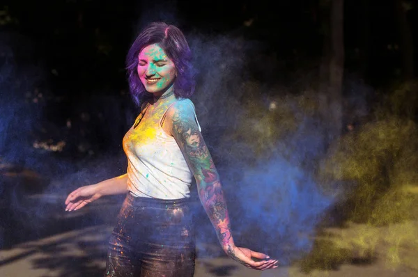 Merry woman with blue and yellow Holi powder exploding around he — Stock Photo, Image