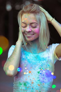 Holi boya yüzünde col ile poz ile memnun sarışın kadın