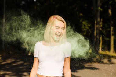 Beyaz t gömlek ile sürpriz genç kadın boya Holi patlayan