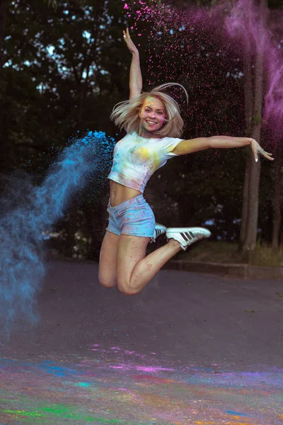 Mutlu genç kadın onun yanında patlayan Holi Tozu ile atlama