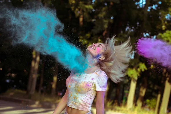 Mujer rubia expresiva con el pelo en movimiento jugando con Holi po — Foto de Stock