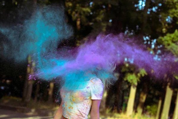 Cloud of dry colorful powder Holi exploding around young blonde — Stock Photo, Image