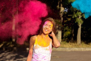 Holi patlayan ile poz kısa saçlı tabaklanmış kadın gülüyor
