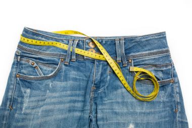 Blue jeans and the measure tape on a white background