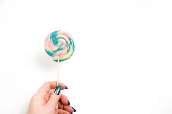 Mano femminile che tiene caramello colorato dolce su uno sfondo bianco — Foto Stock