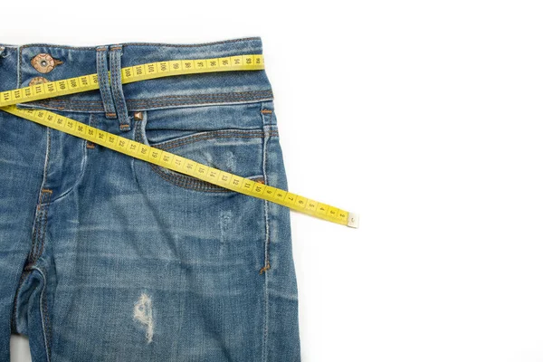 Blue jeans and the measure tape on a white background. Empty spa — Stock Photo, Image