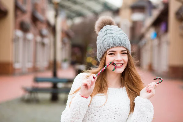 Adorable blonde girl having fun with Christmas candy cane at the — Stock Photo, Image