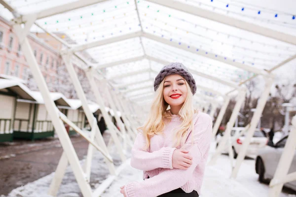 Happy young woman wearing knitted hat and sweater, posing at the — Stock Photo, Image