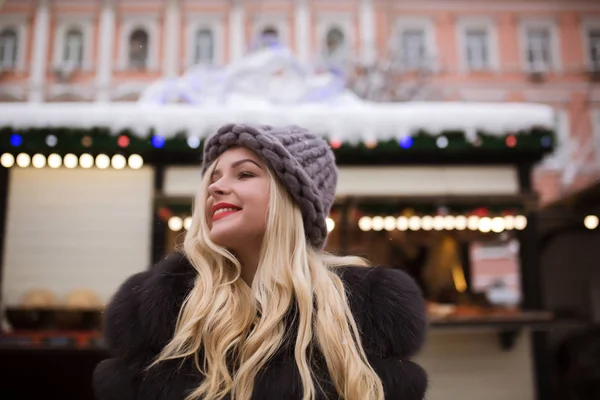 Urban portrait of joyful blonde woman wearing knitted hat and fu — Stock Photo, Image