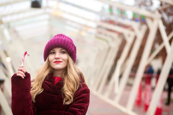 Smuk blondine pige i rød strikket hat udgør med slik stok - Stock-foto