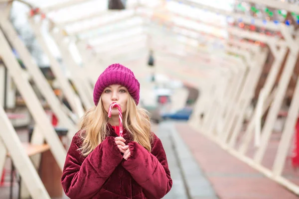 Funny young blonde woman in red knitted hat posing with candy ca — Stock Photo, Image