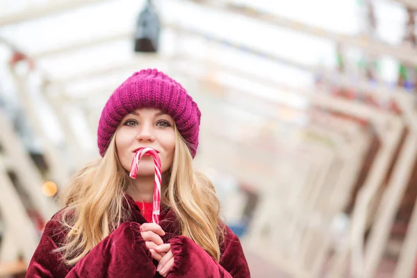 Positive blonde woman in red knitted hat posing with candy cane — Stock Photo, Image