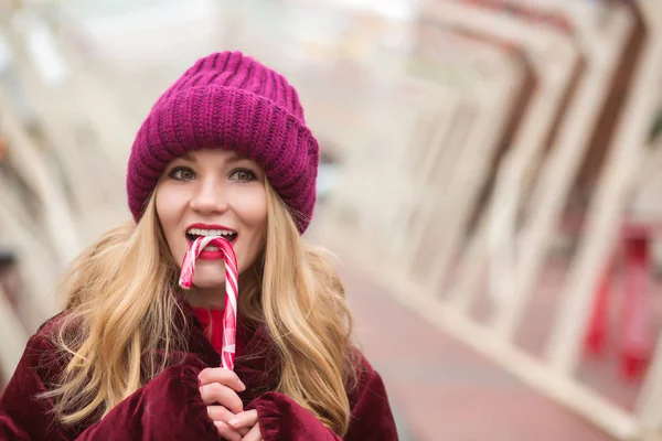 Nice young blonde woman in red knitted hat posing with candy can — Stock Photo, Image