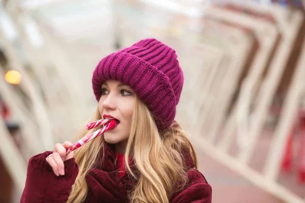 Attractive blonde woman in red knitted hat posing with candy can — Stock Photo, Image