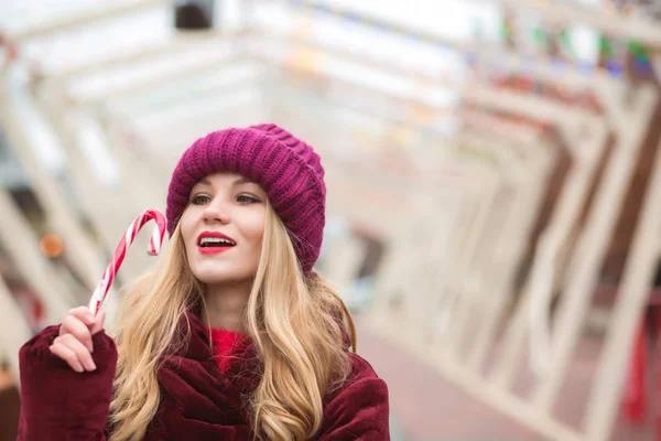 Lovely young woman in red knitted hat posing with candy cane at — Stock Photo, Image